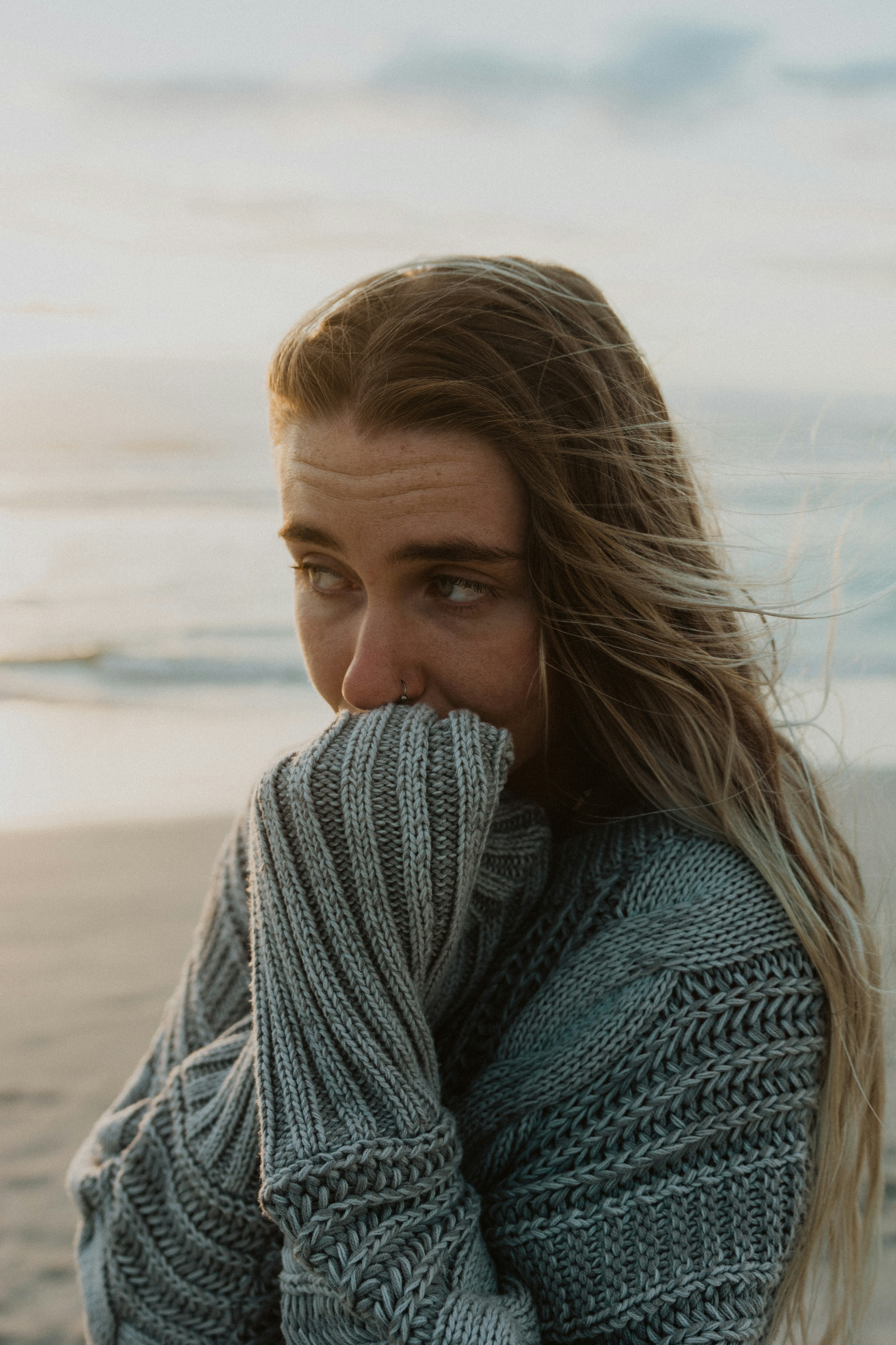 woman in gray knit sweater on beach during daytime